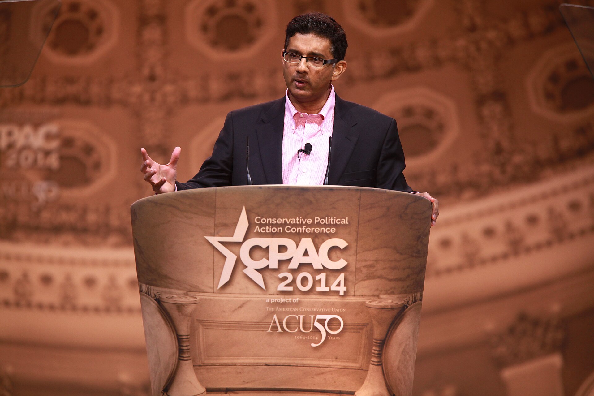Dinesh D'Souza speaking on stage at a conference