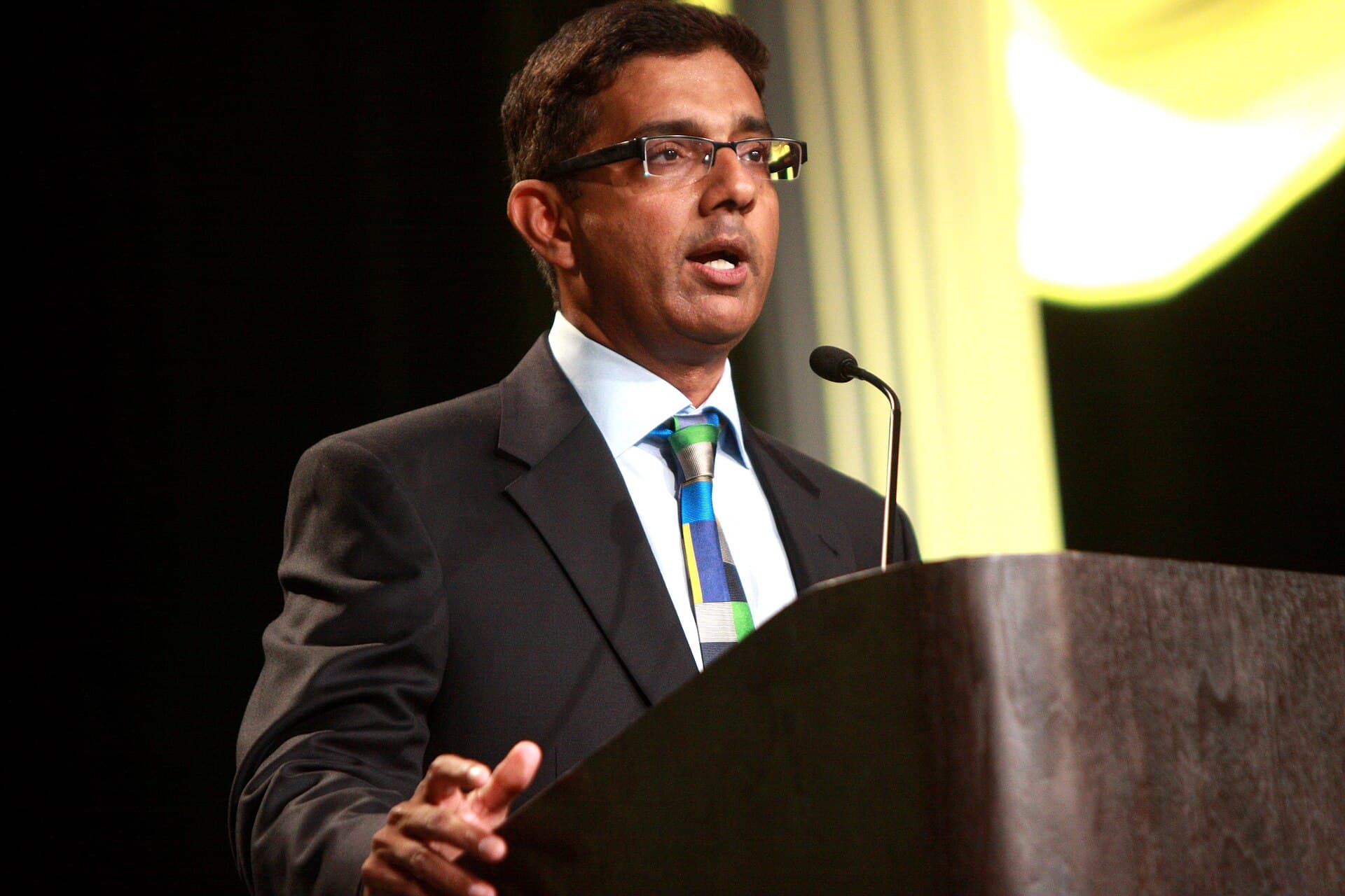 Dinesh D'Souza speaking at a conference podium