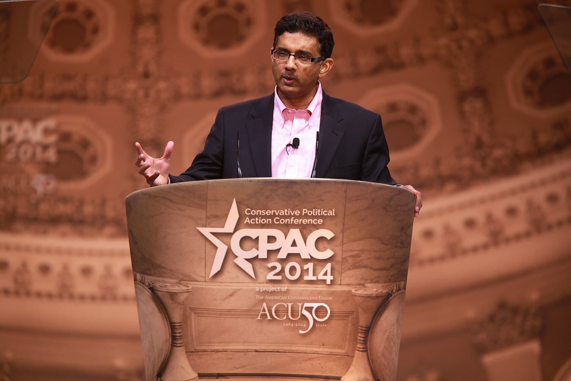 Dinesh D'Souza speaking on stage at a conference